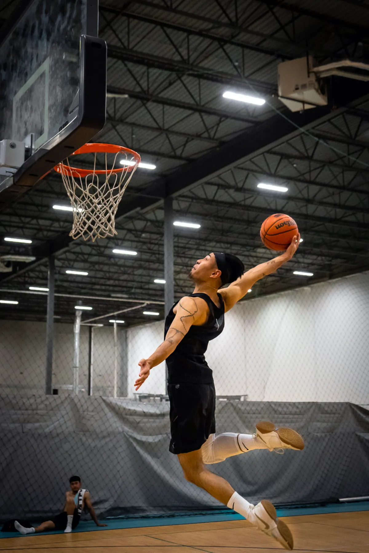 Basketball player rising toward the hoop on an indoor court.