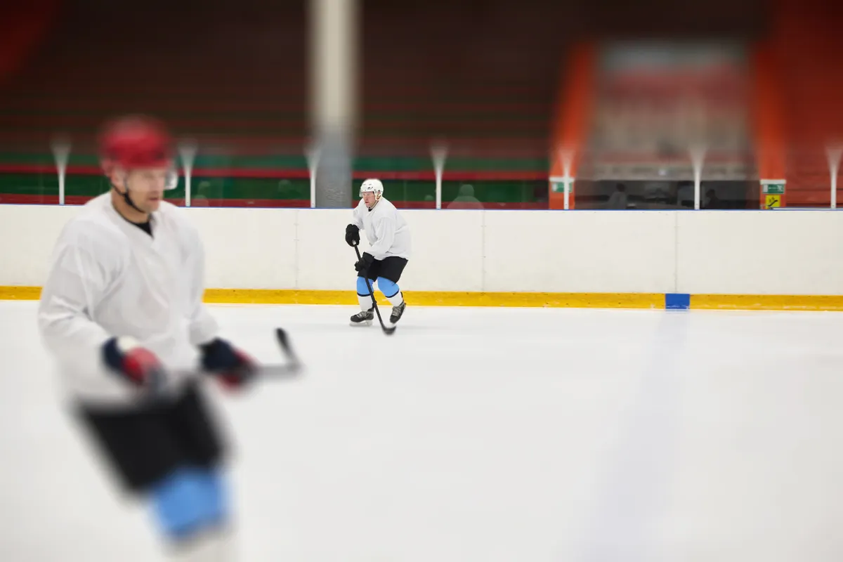 Ice hockey players skating during practice at an indoor rink.