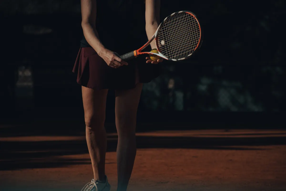 Tennis player holding a racket and ball before a serve on a clay court.